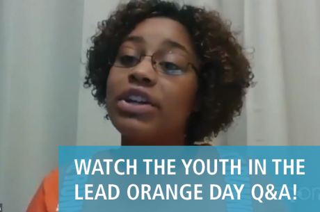 Marissa Williams, a Youth Speaker at the Orange Day Q&A event, is speaking. She is a young black woman who wears glasses and an orange shirt. In front of her image is the text "WATCH THE YOUTH IN THE LEAD ORANGE DAY Q&A!" There is a semi-translucent blue background behind the text.