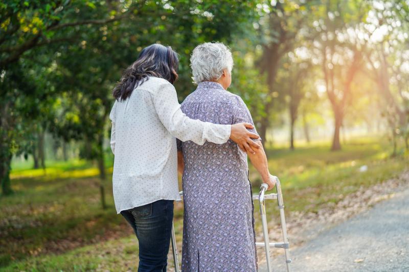 This is a photo of someone supporting an elder, who is using a walker.