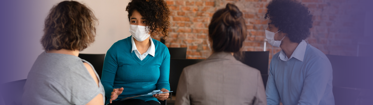 This is an image of four people wearing masks and talking.