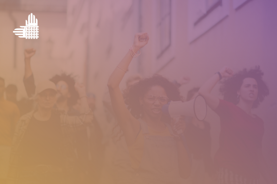 A diverse group of activists raise their fists in the air at a march. In the center is a Black person with shoulder-length curly hair and glasses, shouting into a microphone. On either side is an individual in their 20s or 30s with light skin and curly brown shoulder-length hair--and an elder with light skin, a beige hat, and glasses. Overlaid on top of the photo is a goldenrod to purple gradient. In the upper right-hand corner is an element of the Partnership's logo in white--intertwined hands.