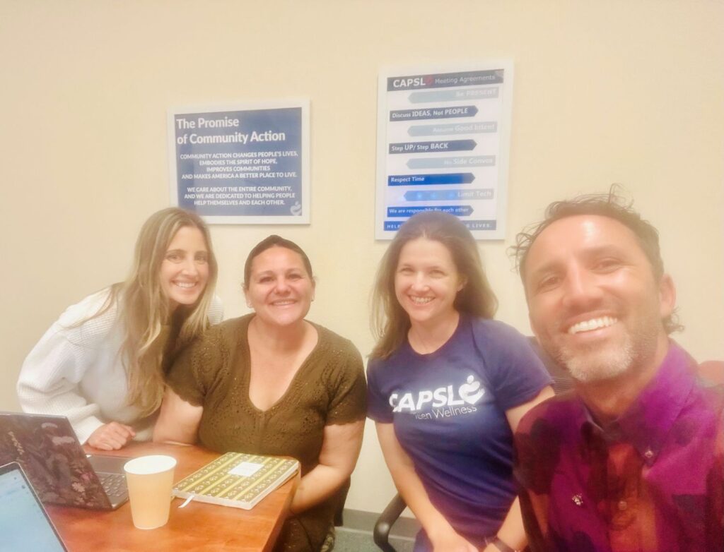 Four adults smiling for a photo in an office setting